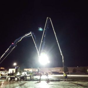 Workers pouring slab under lights at night