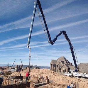 Boom extending over construction site to pour basement wall